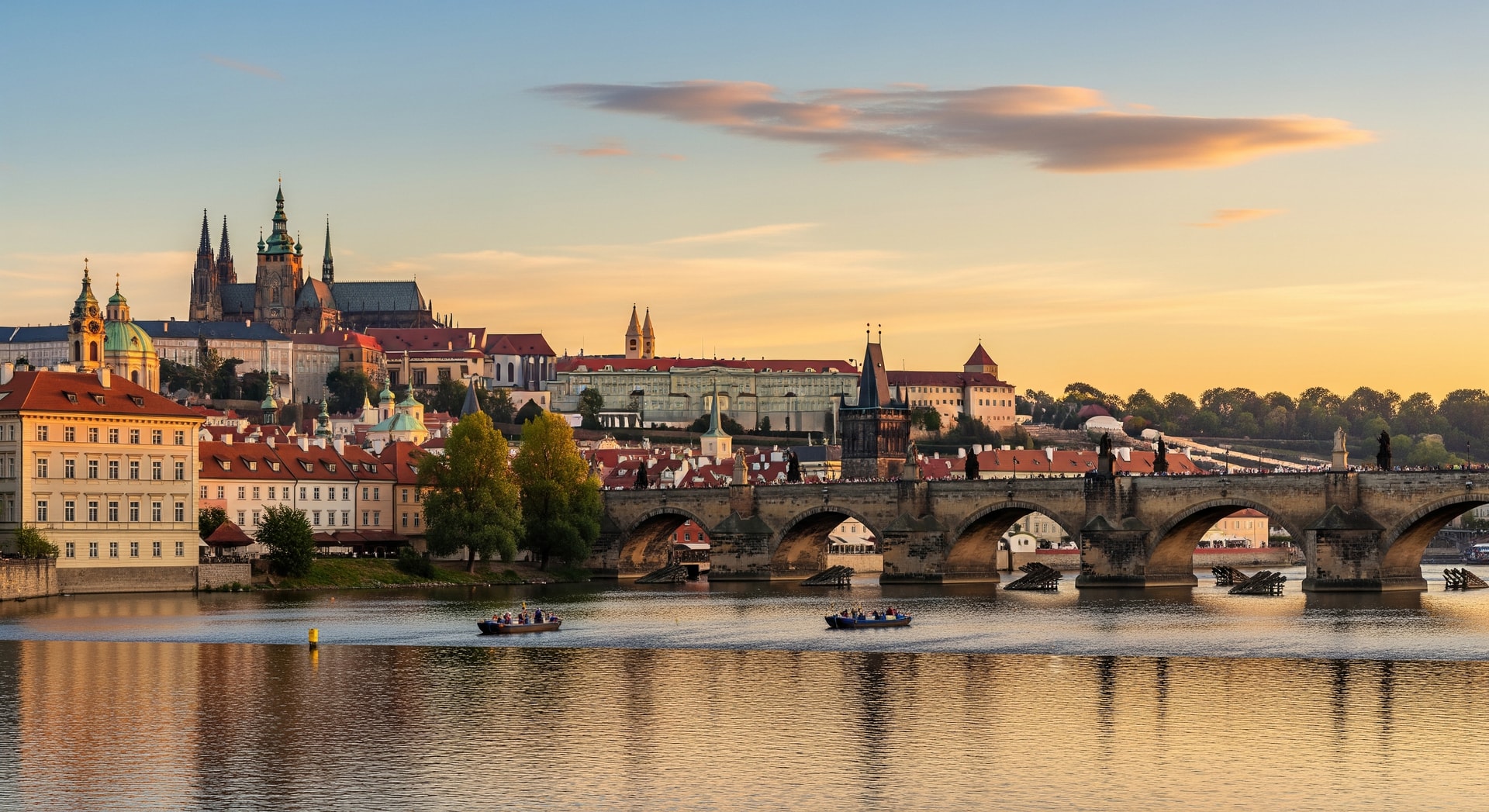 Prague Castle and Charles Bridge over the Vltava River at golden hour representing the Czech Republic's rich cultural and institutional heritage