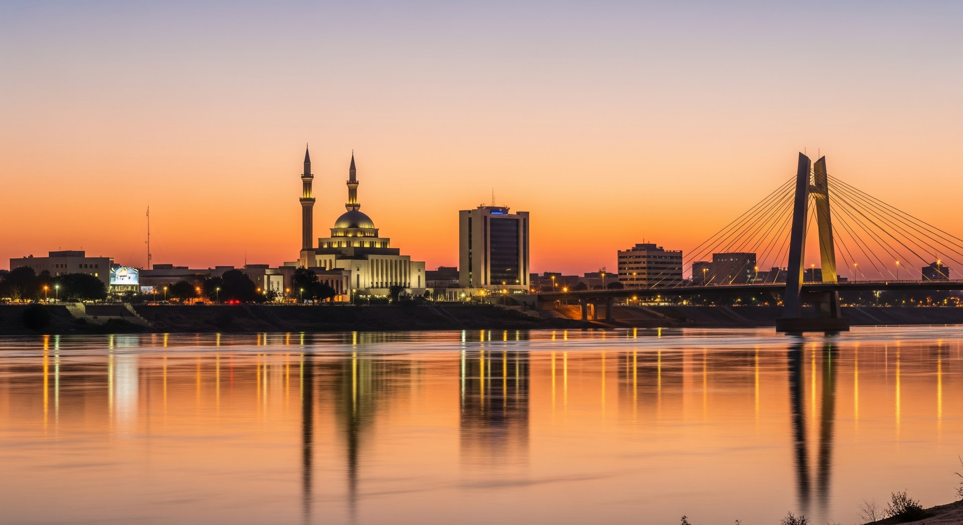Niamey skyline along the Niger River at dusk with the Grand Mosque and the Kennedy Bridge visible against a warm sky representing Niger's capital city