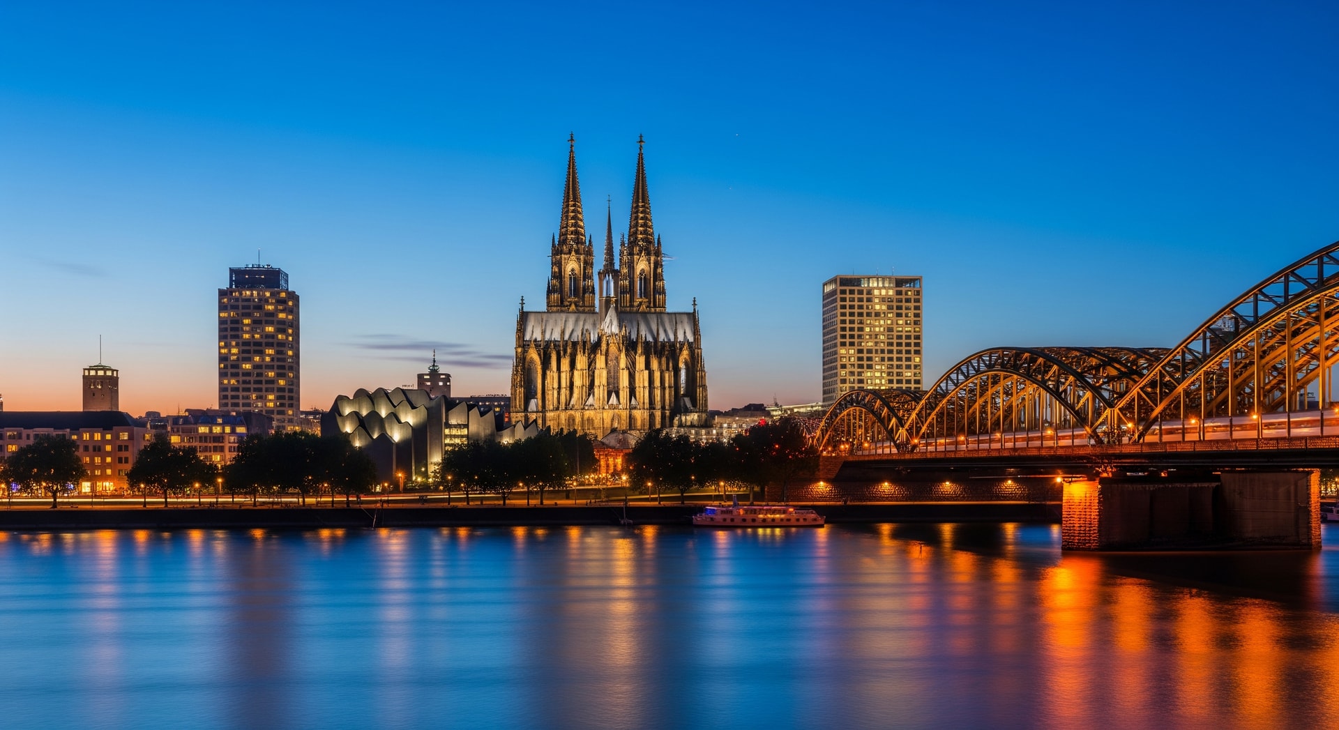 Cologne city skyline with illuminated cathedral and hotel buildings at dusk